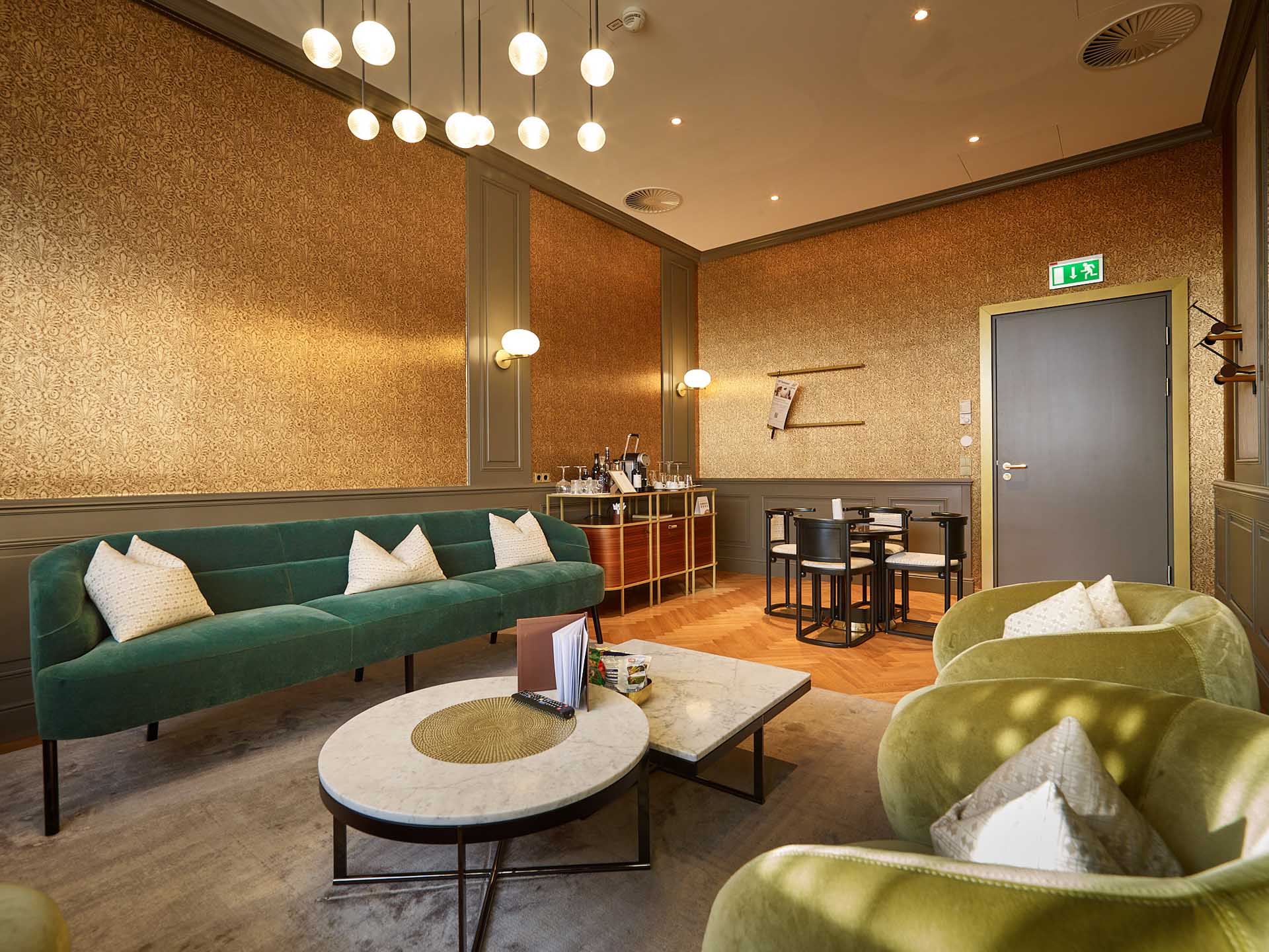 Elegant VIP lounge area with green sofas, armchairs, coffee tables, and stylish lighting at Vienna International Airport.